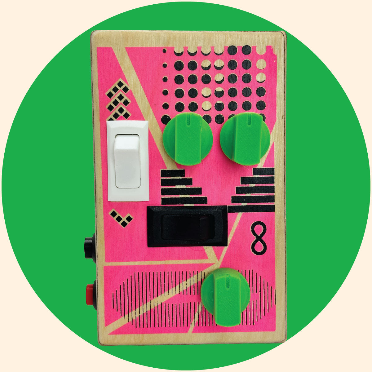 Pink and black graphic design on a  baltic birch wood box. The sound  device has green control knobs, white and black rocker switches